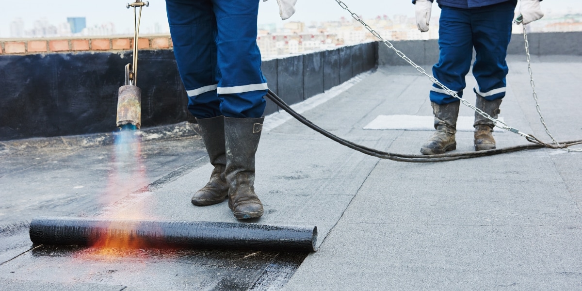 Torch-down roofing installation highlights durability compared to metal roofing in the metal vs. modified bitumen debate.