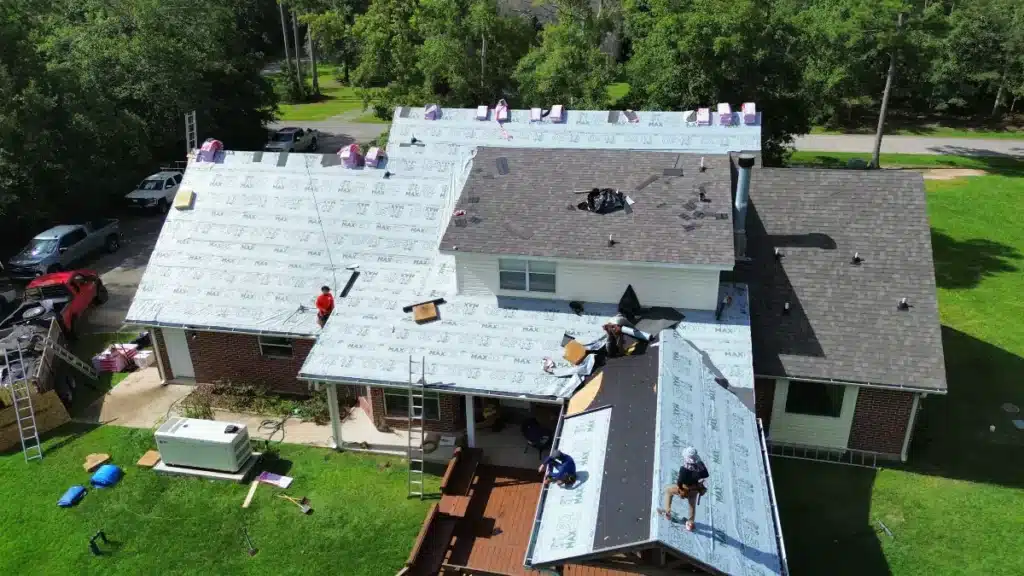 Priority Roofing crew installing underlayment and prepping decking for shingle replacement on a residential home, with roof partially stripped and materials staged for a full roof replacement.