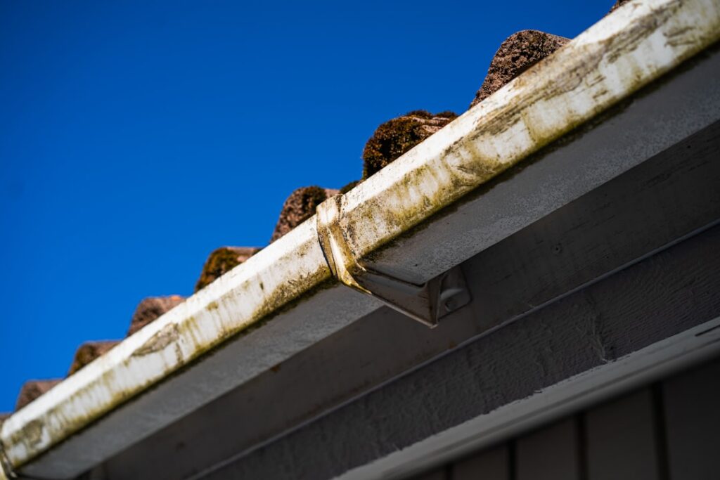 Professional roofer wearing safety gear carefully installs new architectural shingles on a residential roof on a bright, s...