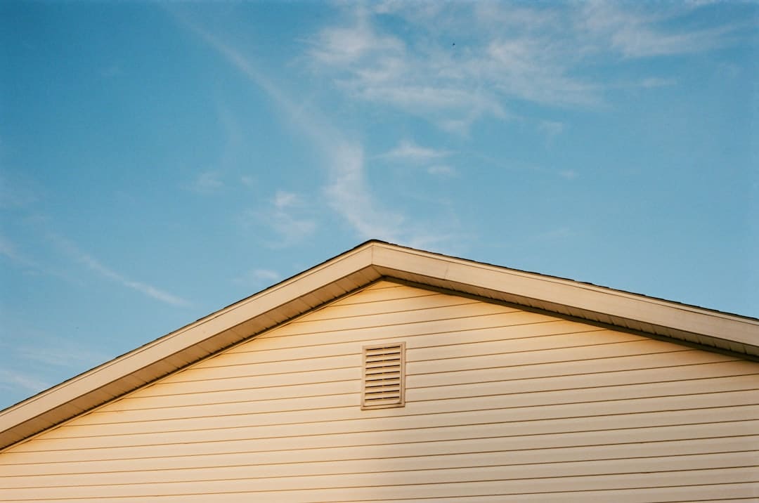 A close-up shot of a newly installed asphalt shingle roof on a home under a clear blue sky, symbolizing the security of a local roofer's guarantee.