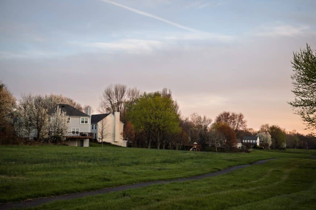 Dramatic storm clouds beginning to part over a quiet suburban neighborhood, suggesting the calm and assessment phase after...