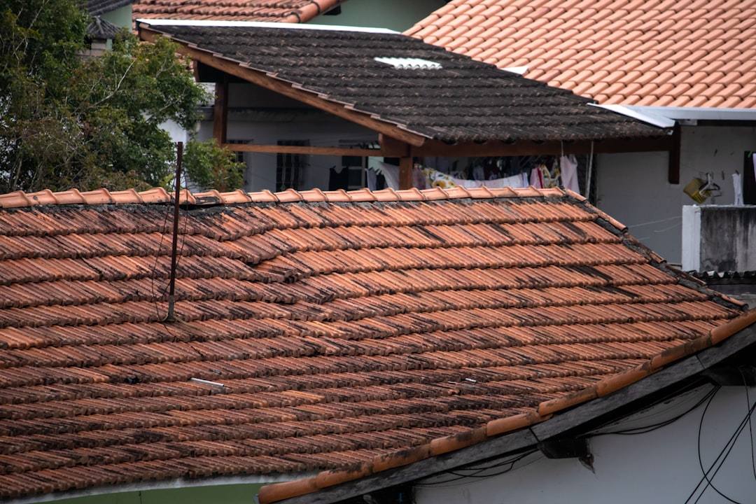 A professional roofer in safety gear carefully installing high-quality architectural shingles on a residential roof, showcasing expert craftsmanship.