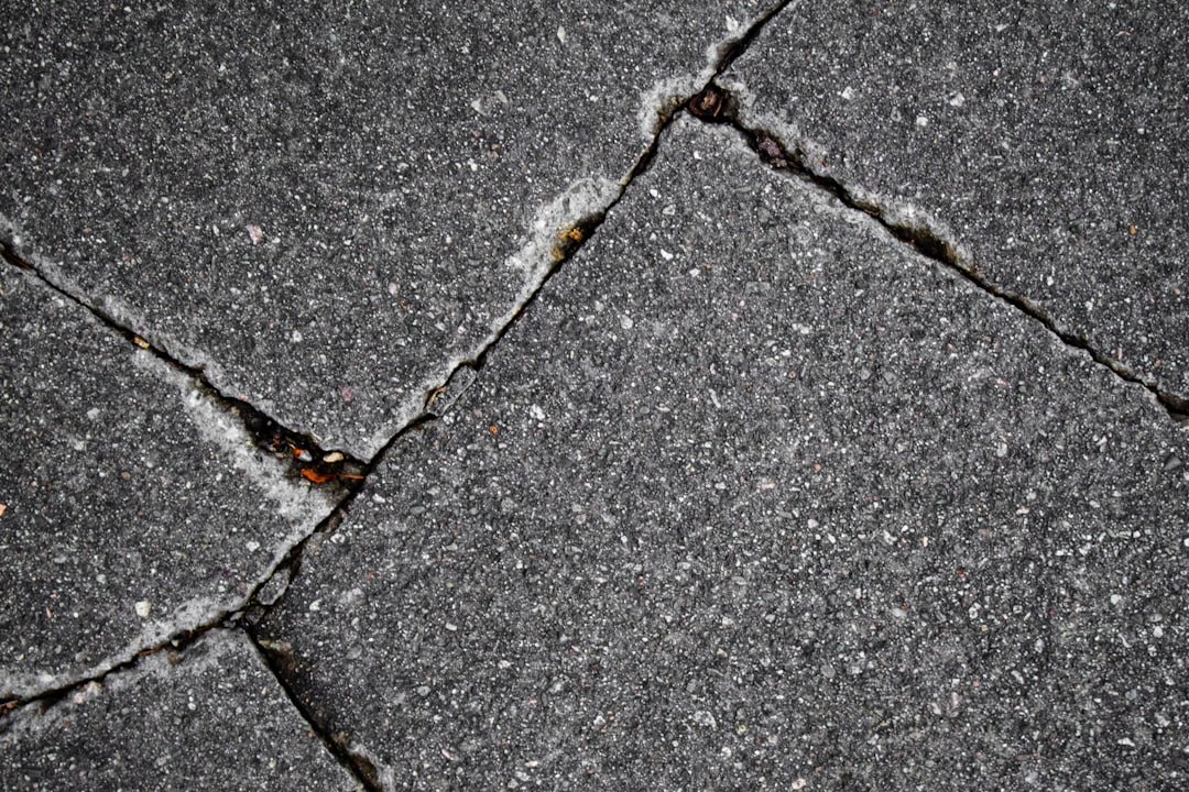 A detailed close-up photo of weathered and slightly lifted asphalt roof shingles, illustrating the subtle, cumulative damage caused by repeated storms.