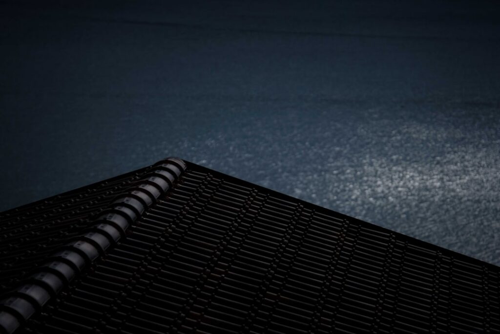 Dramatic close-up of asphalt roof shingles under the intense, bright sun, showing the texture and heat affecting the surface.