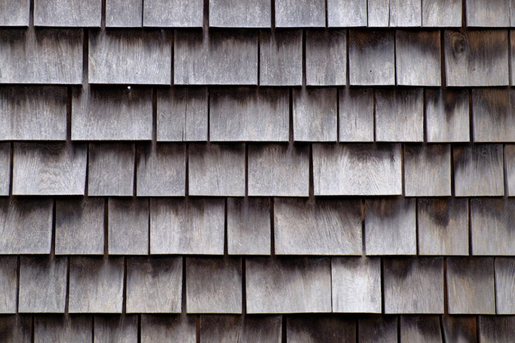 Pristine, newly installed dark architectural shingle roof on a modern suburban home, viewed from a low angle against a bri...