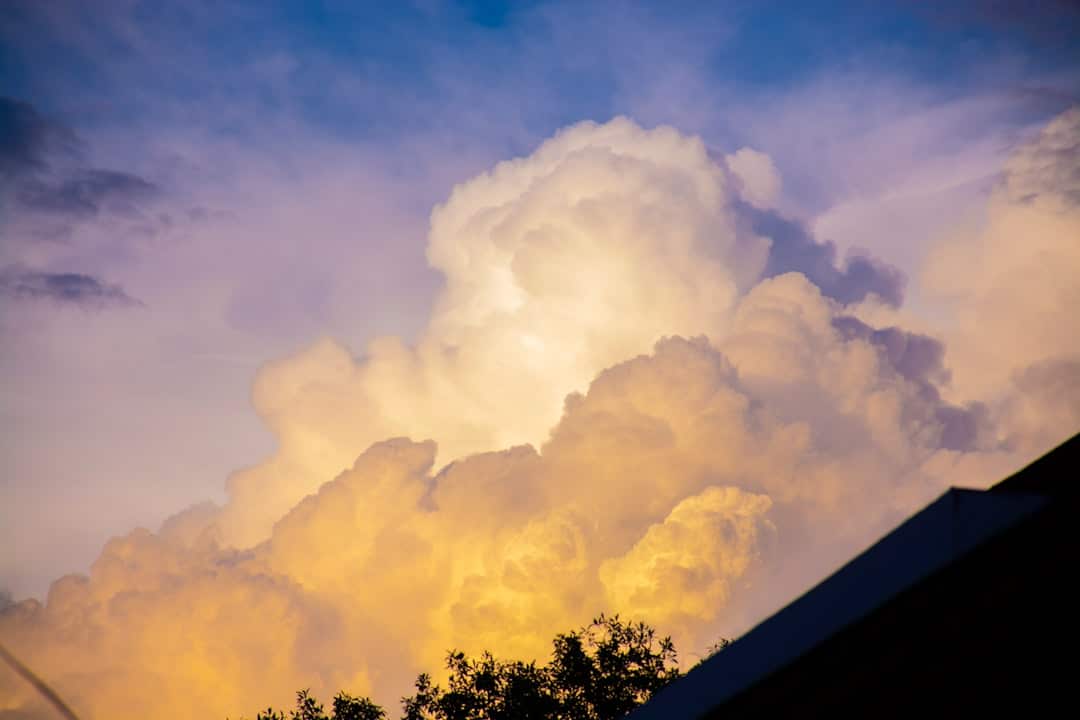 A residential home with its roofline silhouetted against a dramatic, moody sky of dark post-hurricane clouds, creating a sense of foreboding.