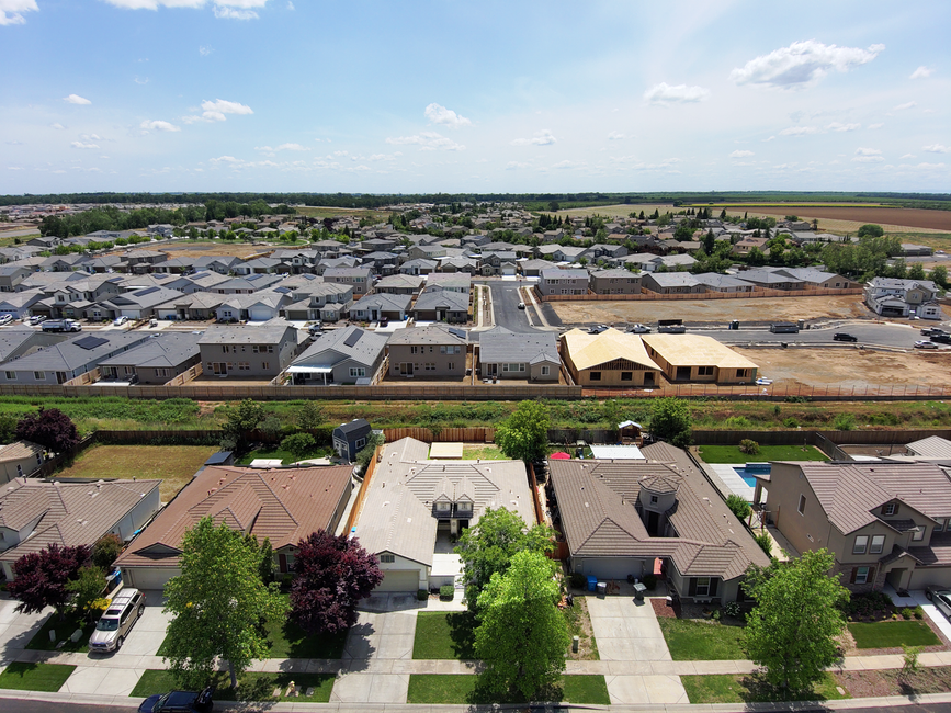 An aerial drone shot captures a newly installed, pristine white flat roof on a modern commercial building, reflecting the bright sun under a clear blue sky.