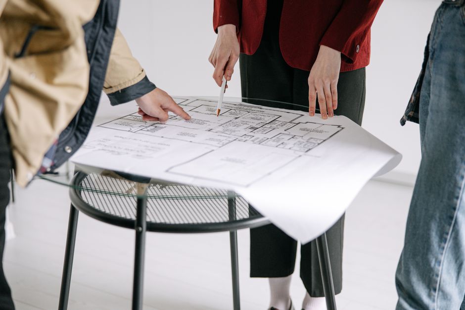 A commercial property manager and a roofing contractor in professional attire reviewing plans on a tablet while standing on a large, clean commercial roof.