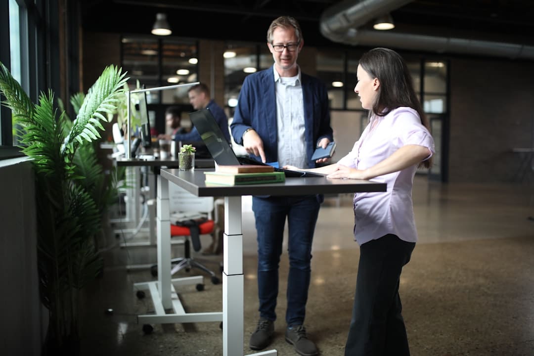 A diverse group of professionals in a bright, modern meeting room, collaborating and reviewing architectural blueprints for a large construction project.