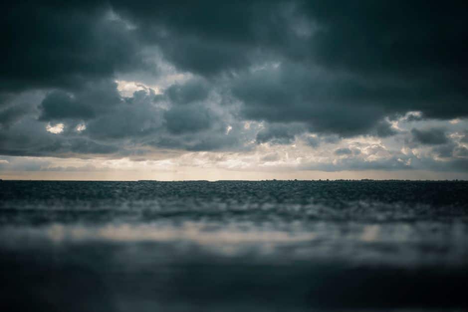 Powerful image of dark, swirling hurricane clouds gathering over a resilient coastal home, symbolizing the threat of Louis...