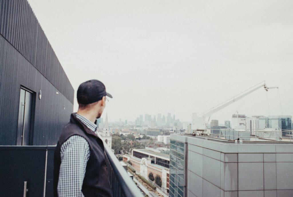 Professional roofing contractor in safety gear carefully inspecting the surface of a large, modern commercial flat roof un...