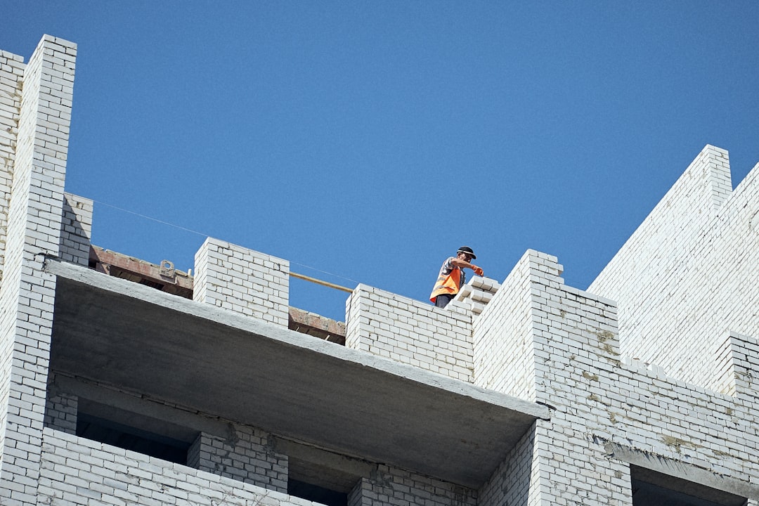 A skilled roofer in safety gear meticulously installing high-quality, durable architectural shingles on a roof, showcasing expertise and modern construction.