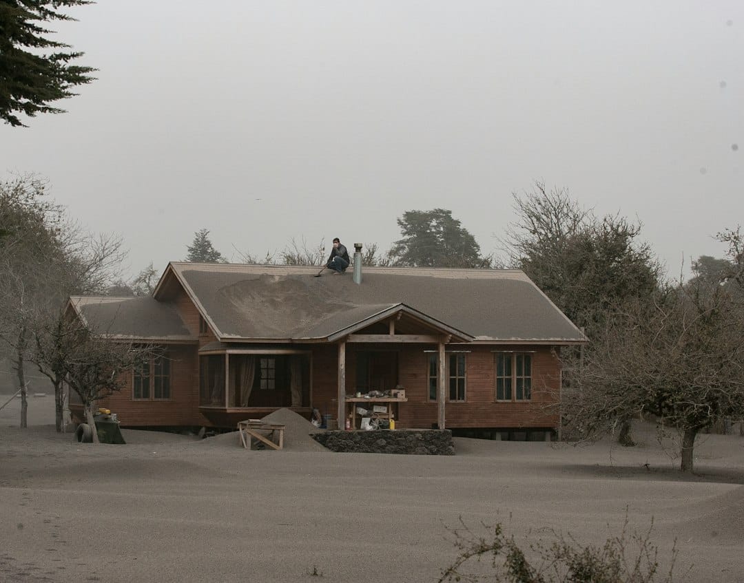 A trustworthy local roofer stands with a homeowner, pointing to the roof and discussing repair plans in a clear, professional manner.