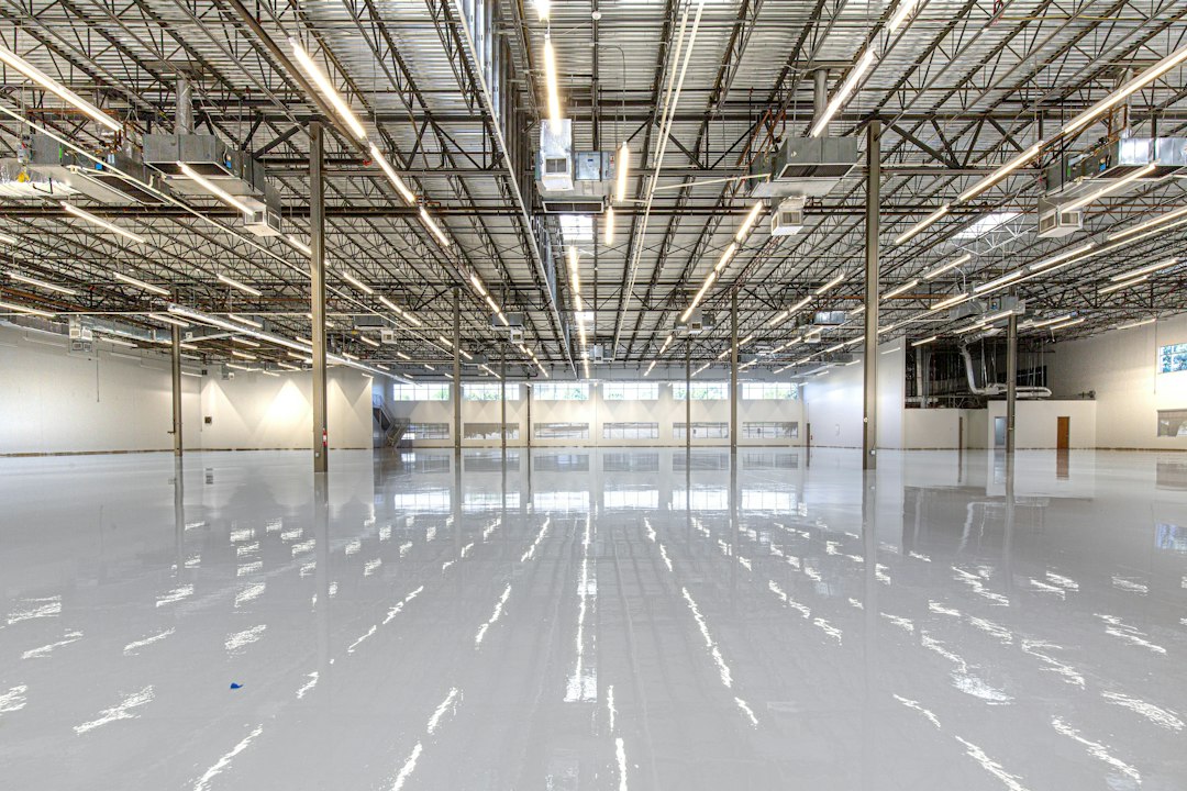 Water-damaged cardboard boxes stacked inside a commercial warehouse, representing the hidden liability of inventory loss from a failing roof.