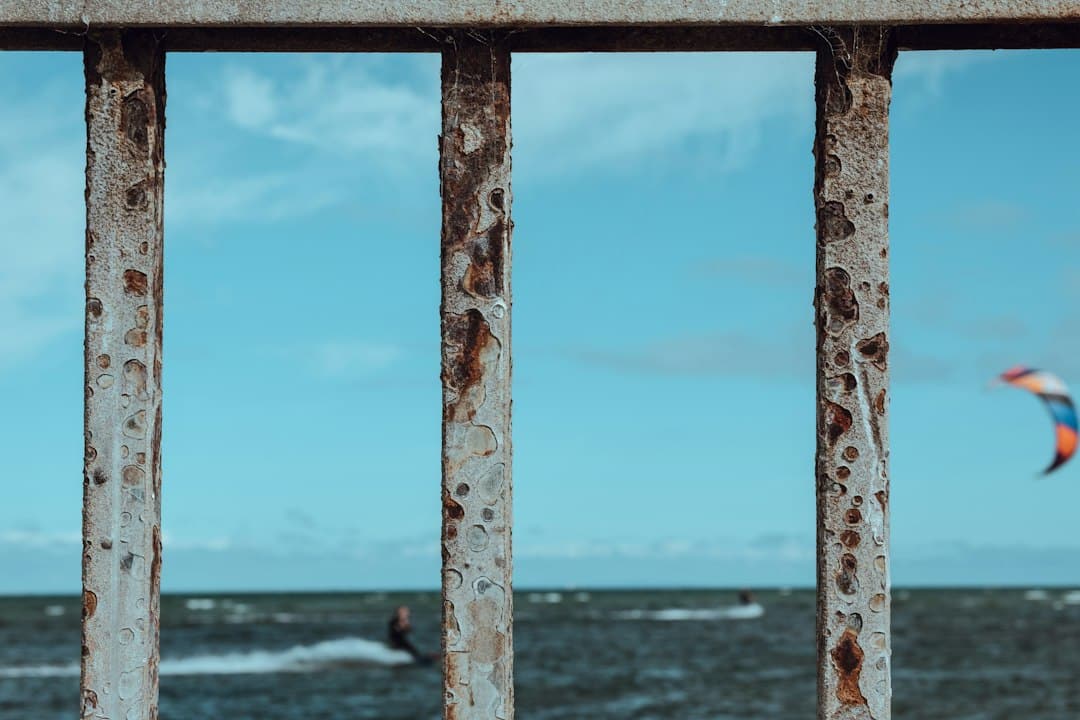A detailed close-up of a weathered metal roof component showing the subtle, corrosive effects of salt air, illustrating the invisible threat to coastal properties.