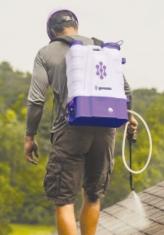 Priority Roofing roofer applying GoNano roof coating with backpack sprayer on asphalt shingles